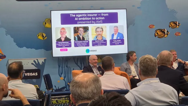 Panelists seated in orange armchairs in the ITC Community Center on the expo floor, beneath a screen showing the session title and speakers.